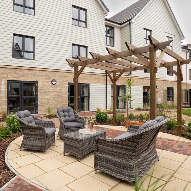 Luxury table and chairs on patio area in front of modern and bright building complex